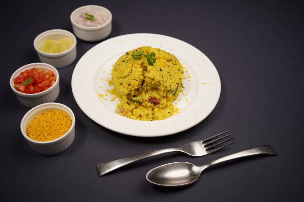 A vibrant serving of Indian poha accompanied by fresh sides, perfect for breakfast.